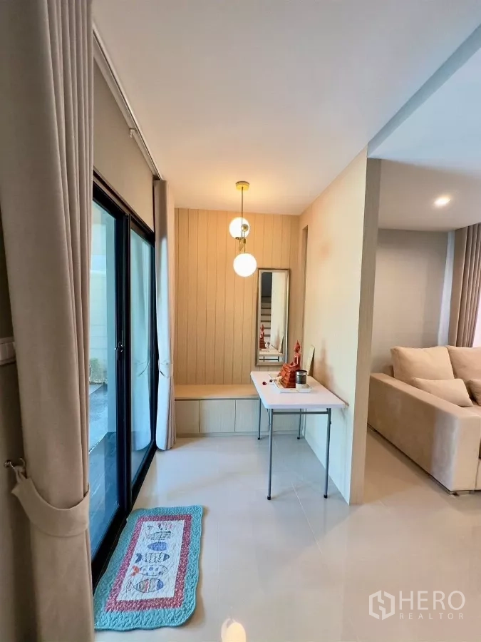 Detached House for rent in Samut Prakan - Hallway with sliding glass door to side patio, small console table and pendant lights.