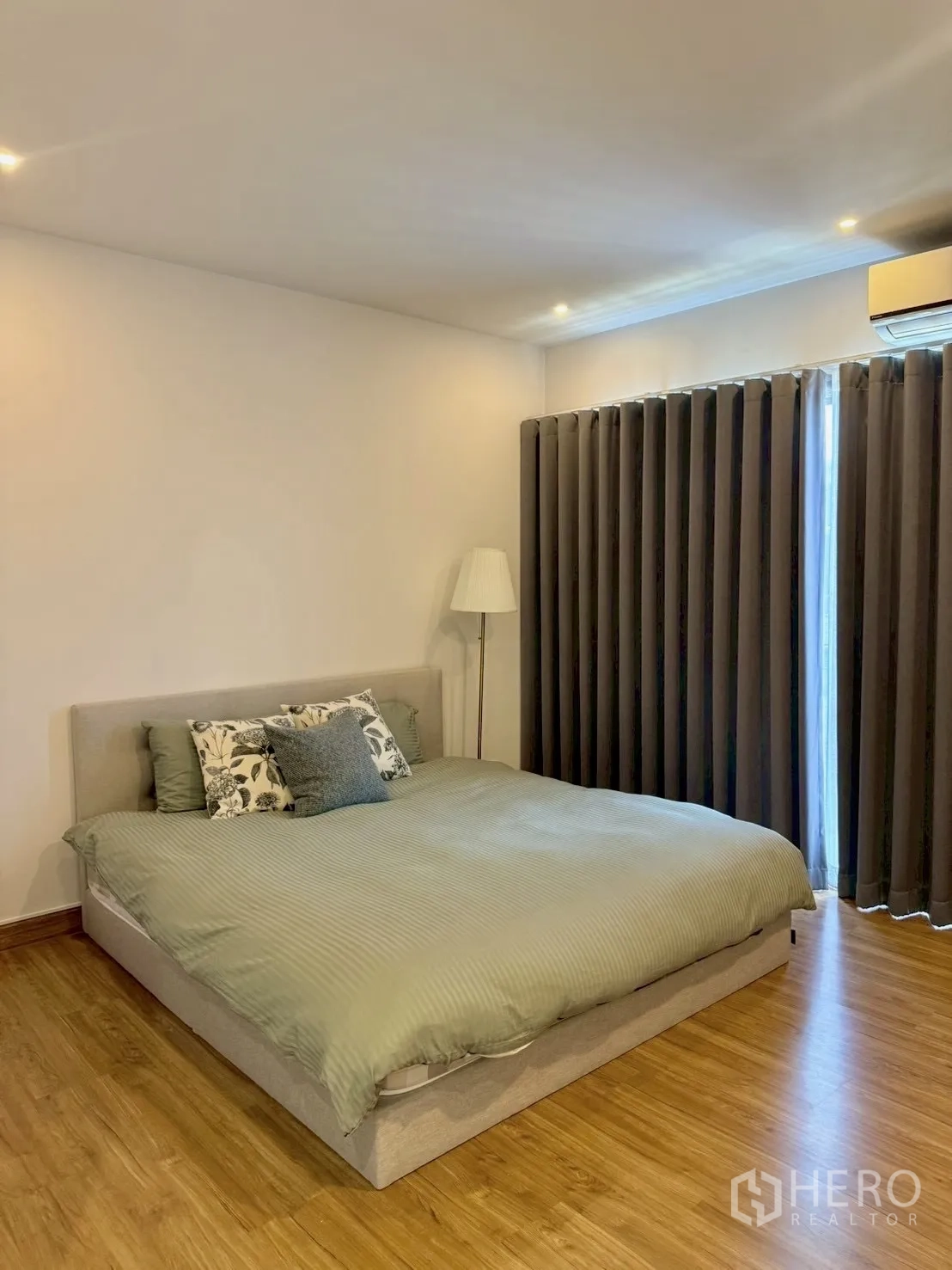 联排别墅 for rent in Prawet, Bangkok - 主卧配双人床、落地灯和空调，木地板。