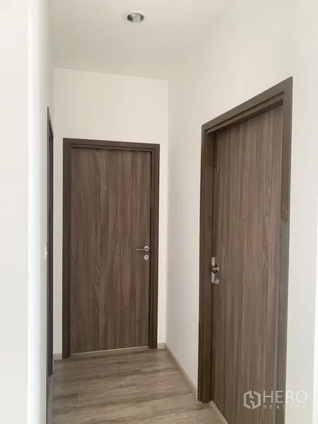 Condominium for sale in Bang Na, Bangkok - Condo corridor with light wood flooring and matching wooden doors.