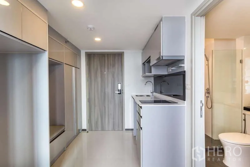 Condominium for rent or sale - Sleek corridor kitchen with overhead cabinets and bathroom doorway.