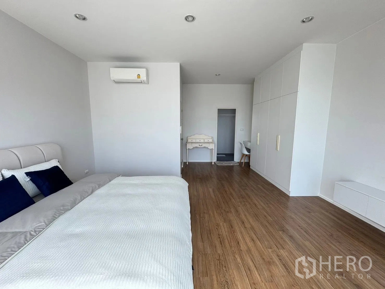 Townhouse for rent in Saphan Sung, Bangkok - Spacious master bedroom with wood flooring, built-in wardrobes and desk.