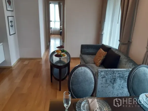 คอนโด ให้เช่าในWatthana, Bangkok - พื้นที่นั่งเล่นและรับประทานอาหารแบบโอเพ่นพร้อมพื้นไม้ และโถงทางเดินไปยังห้องนอน