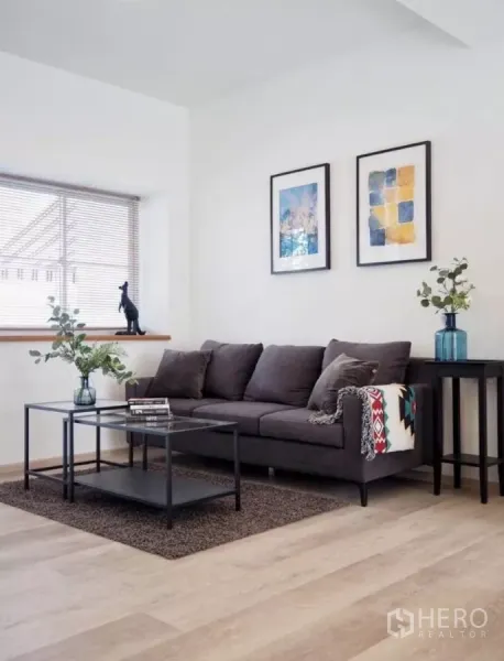 Townhouse for rent in Bang Phli, Samut Prakan - Bright living room with grey sofa, minimalist decor, wood flooring and a wide window with blinds.