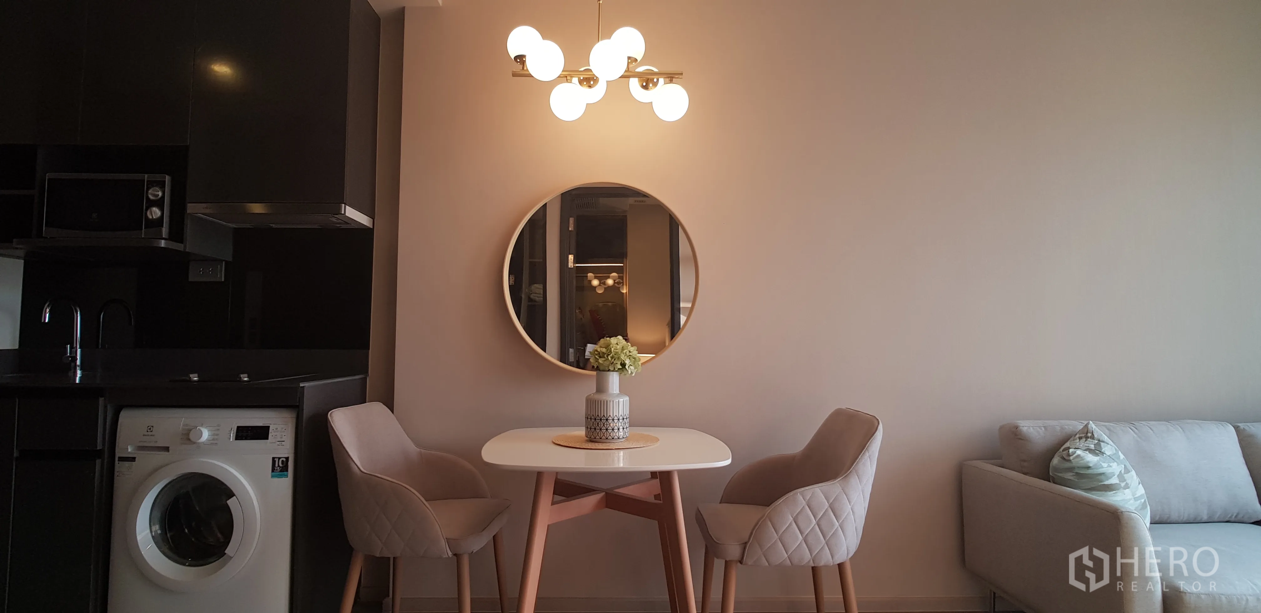 Condominium for rent in Watthana, Bangkok - Compact dining table for two next to a modern kitchenette with washer, microwave and glossy black cabinets.