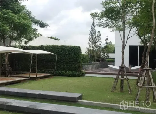 Townhouse for rent in Suan Luang, Bangkok - Communal garden with trimmed hedges, shaded seating decks and open lawn within the townhouse project.