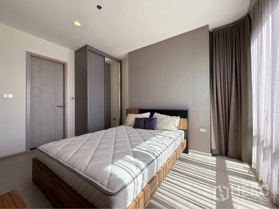 Condominium for rent in Khlong Toei, Bangkok - Cozy room with bed, sliding wardrobe and floor-to-ceiling curtains.