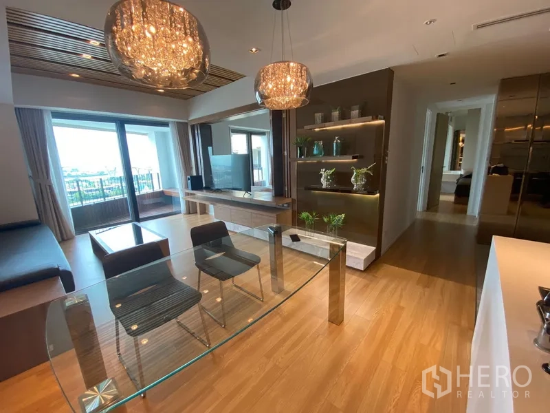 Condominium for rent in Yan Nawa, Bangkok - Open-plan living and dining area with a glass table, sparkling chandeliers and a balcony overlooking the river at The Pano.