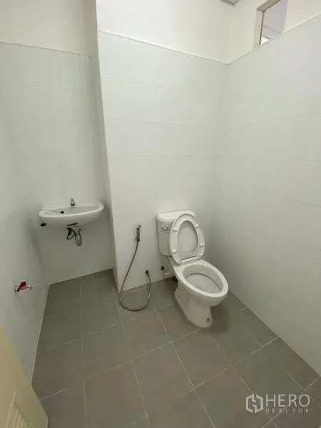 Office Space for rent in Chatuchak, Bangkok - Clean restroom with white tiles, toilet, handheld bidet and wall-mounted sink.