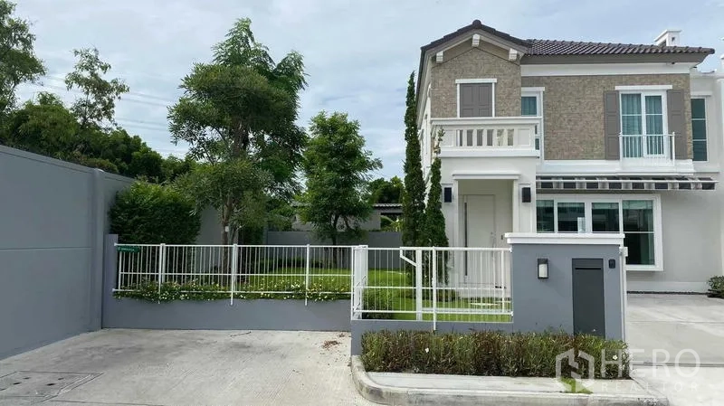 Detached House for rent or sale in Prawet, Bangkok - Front elevation of the detached home with balcony and gated parking.
