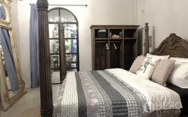 联排别墅 出租在Watthana, Bangkok - 卧室配雕花木床、拱形玻璃门与高大的华丽镜子。