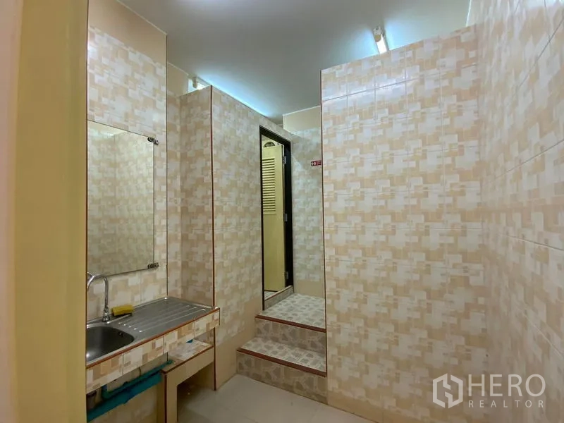 Office Space for rent in Watthana, Bangkok - Restroom area with patterned wall tiles, mirror, stainless sink, and steps to cubicles.