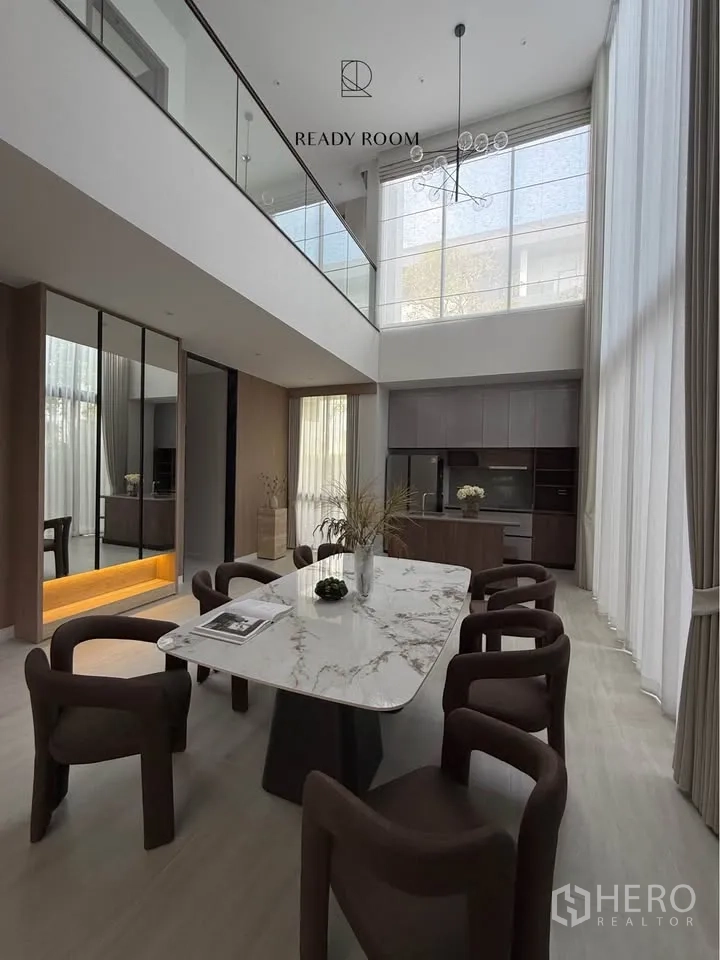 Detached House for rent in Bang Kapi, Bangkok - Double‑height dining room with marble table and chandelier beside the kitchen.