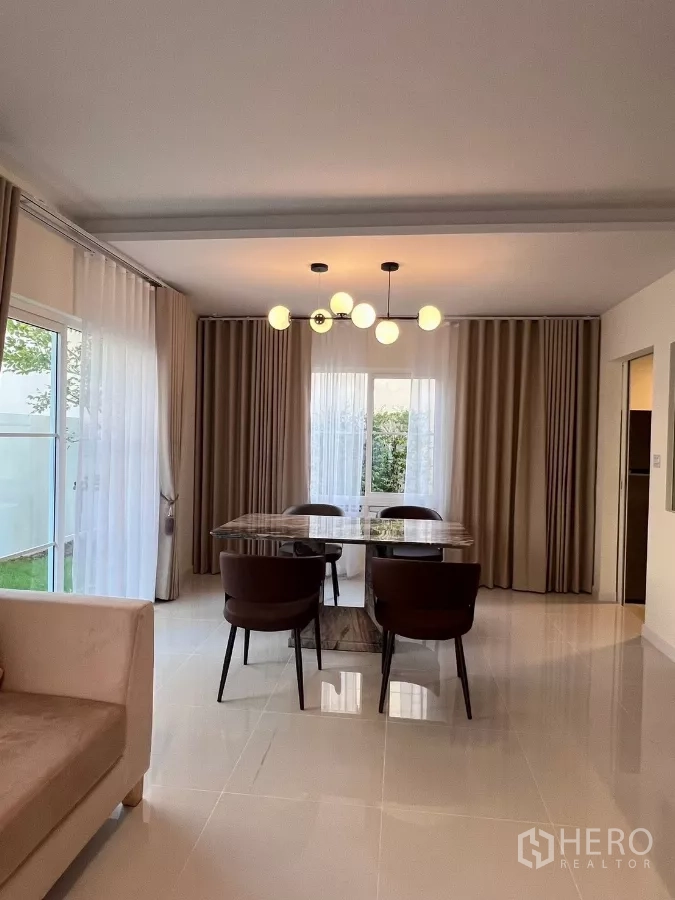 Detached House for rent in Bang Phli, Samut Prakan - Dining room with modern chandelier, large windows and neutral drapes.