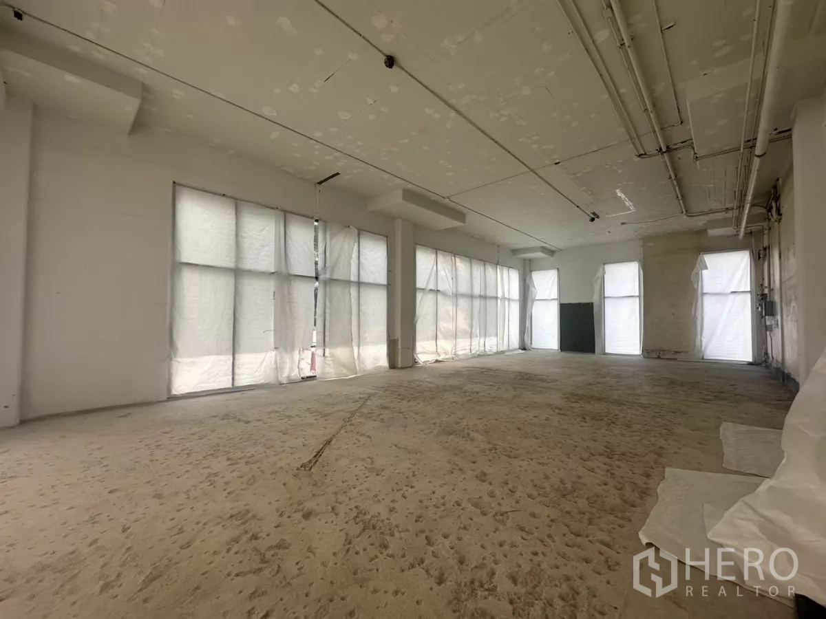 零售空间 出租在Khlong Toei, Bangkok - 毛坯零售内部，高挑天花、外露管线与多扇大窗。