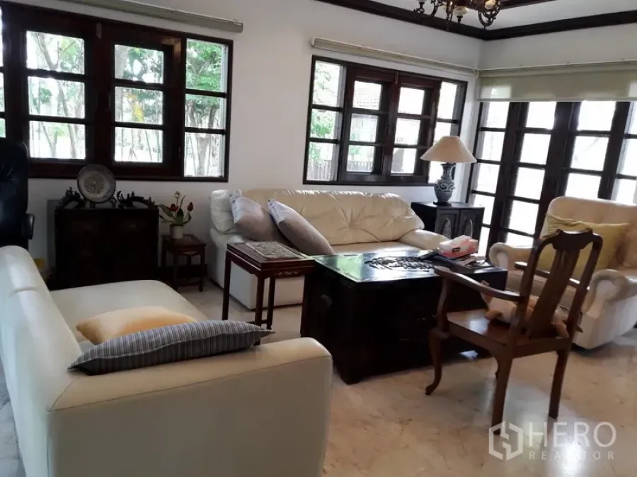 独立式住宅 出租在Bang Na, Bangkok - 明亮客厅，奶油色沙发、木框窗与大理石地面