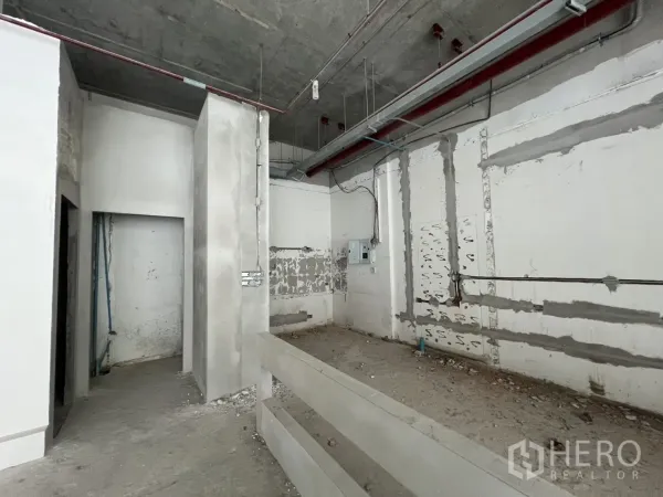 Retail Space for rent in Khlong Toei, Bangkok - Raw concrete retail interior with high ceiling, exposed conduits and partitioned rooms.