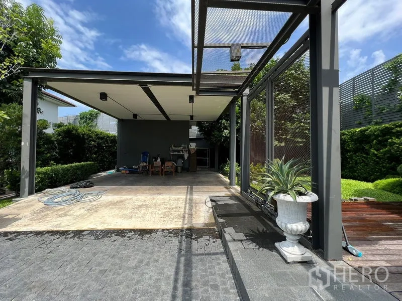 Detached House for sale in Bang Kapi, Bangkok - Covered carport with open patio, potted plants and paved driveway.