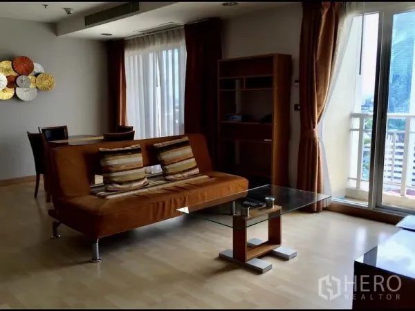 คอนโด ให้เช่าในWatthana, Bangkok - ห้องนั่งเล่นโซฟาสีส้ม โต๊ะกลางกระจก และประตูกระจกออกระเบียงเห็นวิวเมือง