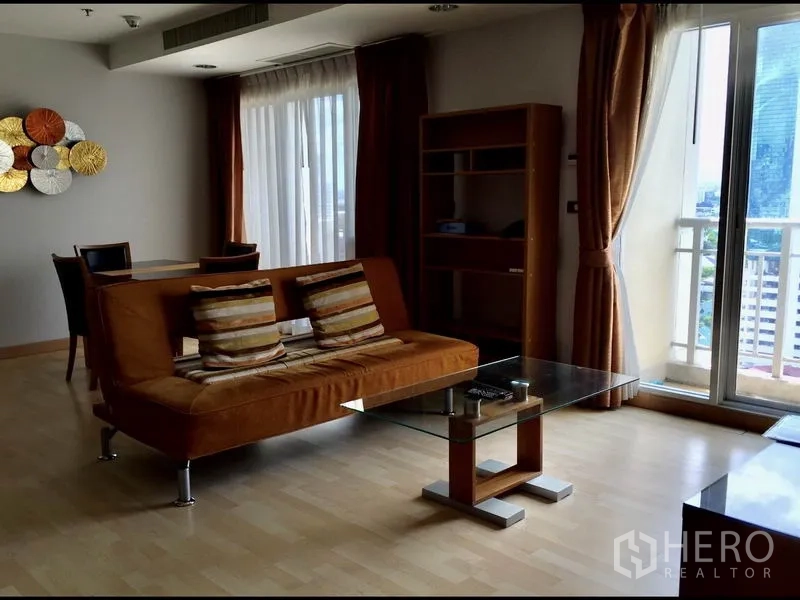 คอนโด ให้เช่าในWatthana, Bangkok - ห้องนั่งเล่นโซฟาสีส้ม โต๊ะกลางกระจก และประตูกระจกออกระเบียงเห็นวิวเมือง