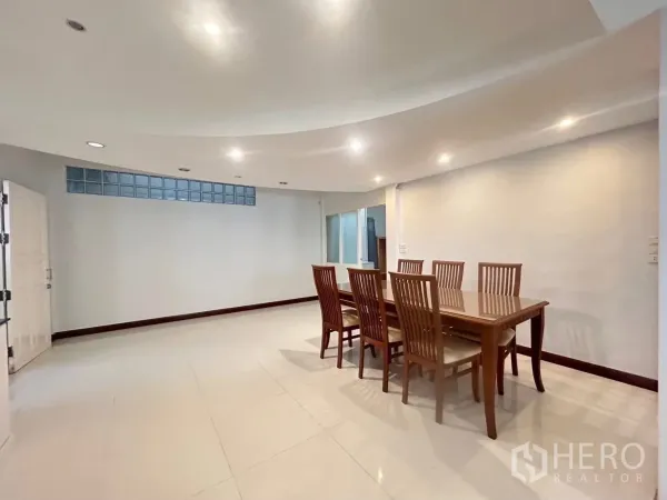 Detached House for rent in Suan Luang, Bangkok - Dining area with an eight‑seat wooden table under recessed ceiling lights.