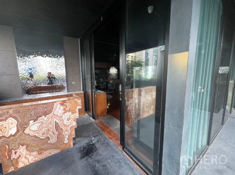 Retail Space for rent - Glass entrance with a stone reception counter and textured feature wall.