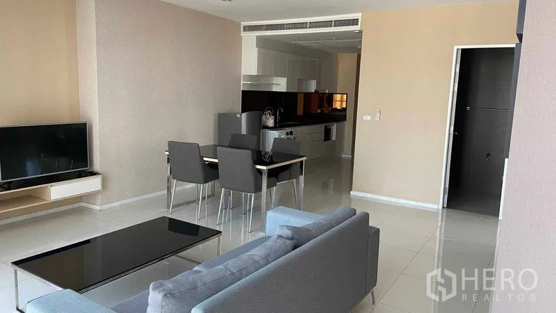 คอนโด ให้เช่าในWatthana, Bangkok - พื้นที่นั่งเล่น–ทานข้าวแบบเปิดโล่ง โซฟาสีเทา โต๊ะกลางสีดำ ชั้นวางทีวี ชุดโต๊ะอาหาร 4 ที่นั่ง และพื้นกระเบื้อง เชื่อมต่อครัว