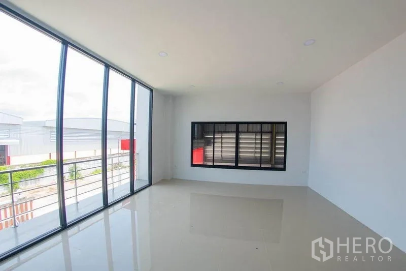 Warehouse for sale in Krathum Baen, Samut Sakhon - Upper office with curved glass wall and balcony railing.