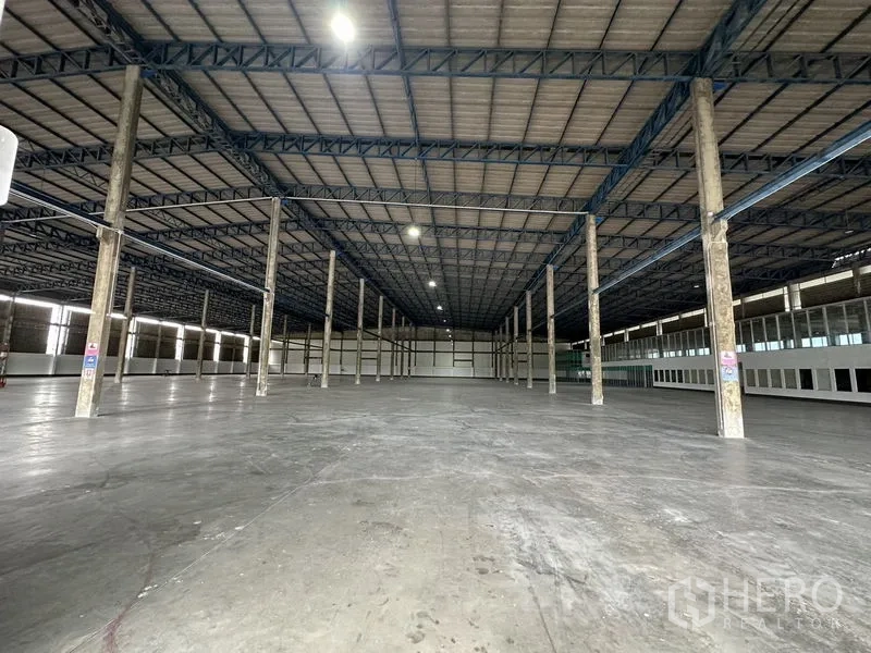 Factory for rent in Bang Sao Thong, Samut Prakan - Open warehouse floor with grid of columns, overhead lighting and polished concrete surface.
