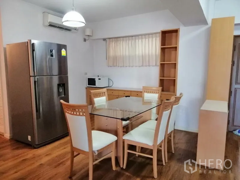 Condominium for rent in Watthana, Bangkok - Dining corner with glass-top table, four chairs, and stainless fridge.