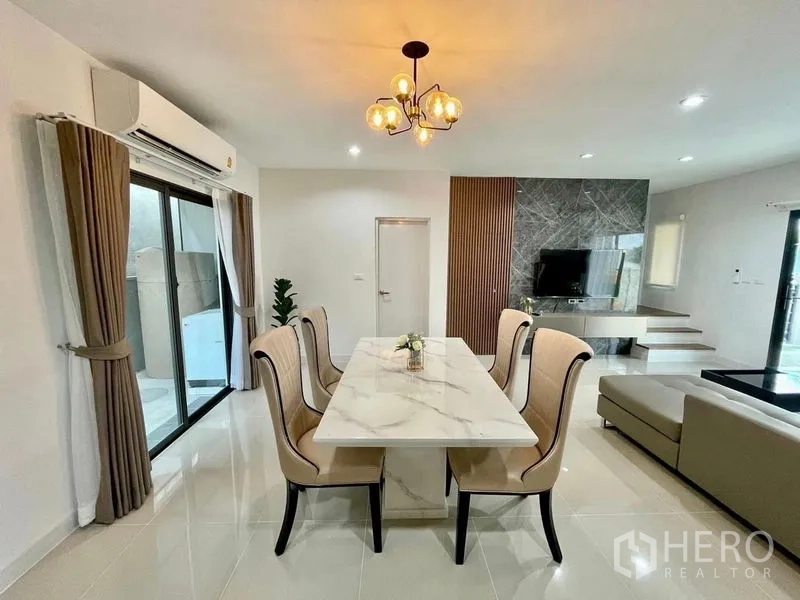 Townhouse for rent in Bang Phli, Samut Prakan - Dining area with marble-top table, chandelier lighting and balcony access next to the living room.
