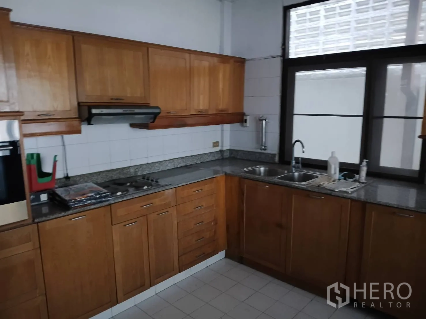 Detached House for sale in Watthana, Bangkok - Secondary kitchen with wooden cabinets, granite counters, and cooktop.