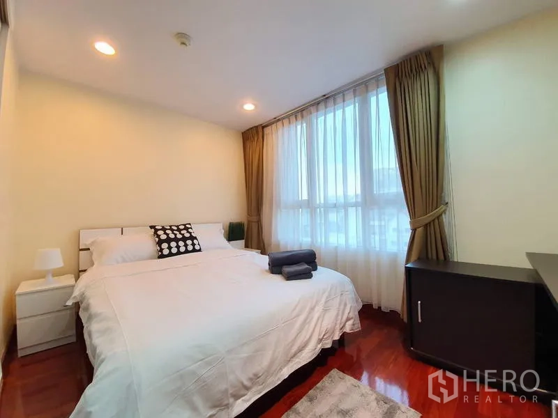 Condominium for rent or sale in Pathum Wan, Bangkok - Cozy second bedroom with bedside tables, warm lighting and sheer curtains.