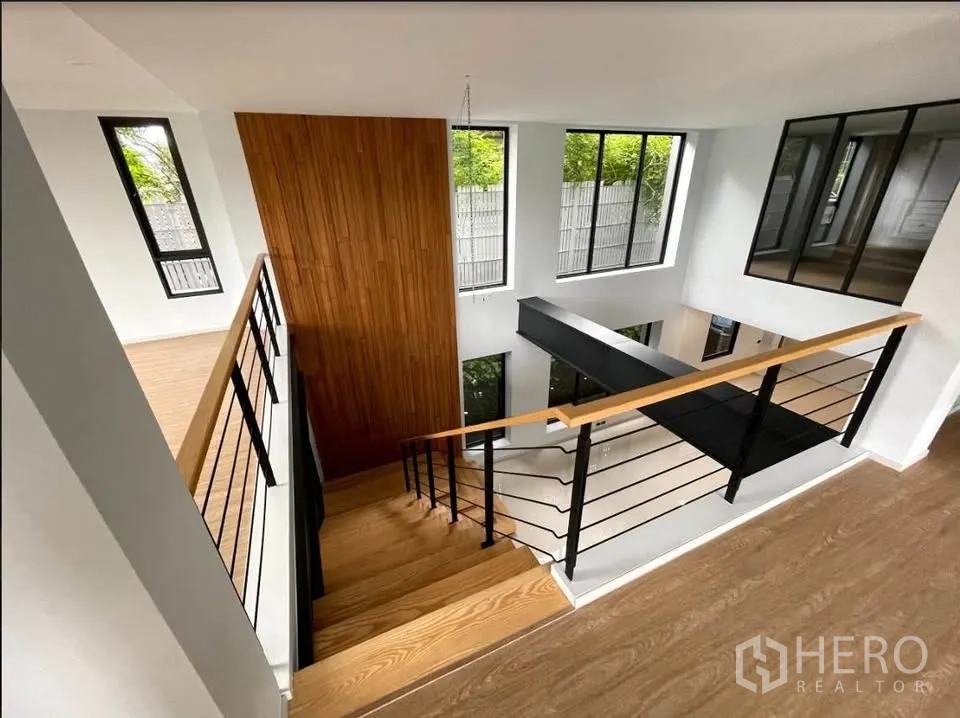 Detached House for sale in Watthana, Bangkok - Stair landing with a feature wood wall and windows around the central void.
