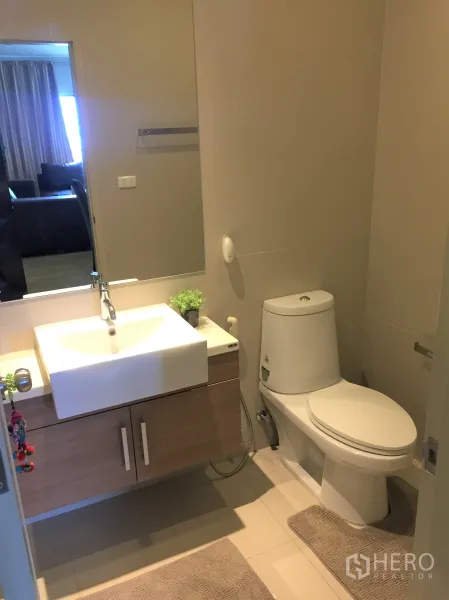 Condominium for rent in Watthana, Bangkok - Second bathroom with white basin, wooden cabinet storage, and clean tiled flooring.