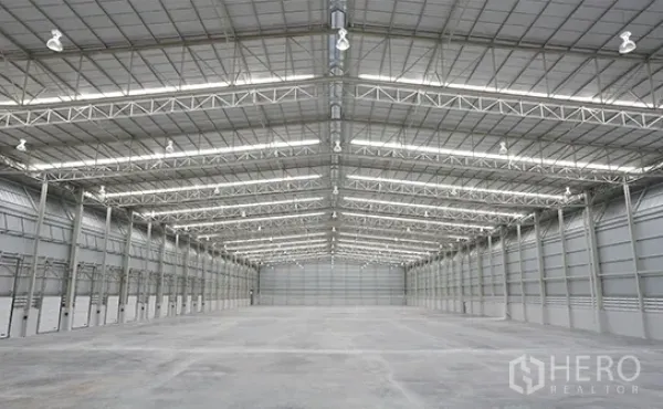Warehouse for rent in Bang Pakong, Chachoengsao - Vast high-clear warehouse interior with steel truss roof, ample lighting and concrete floor.