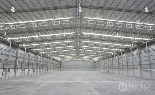 Warehouse for rent in Bang Pakong, Chachoengsao - Vast high-clear warehouse interior with steel truss roof, ample lighting and concrete floor.