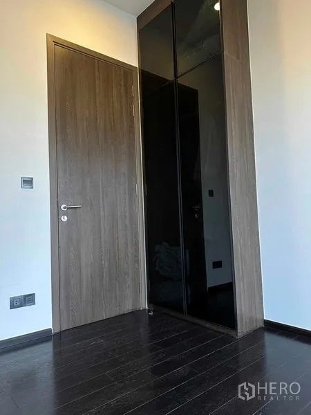 公寓 出租在Khlong Toei, Bangkok - 入户角落，木门与黑色内置衣柜的公寓空间