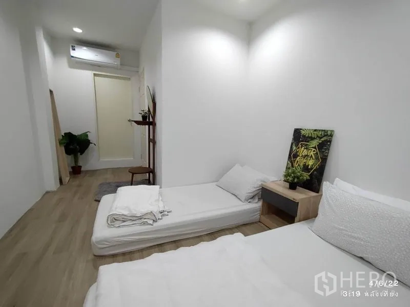 带办公室的家 出租 - 狭长卧室另一角度，带空调、绿植与床头柜装饰。