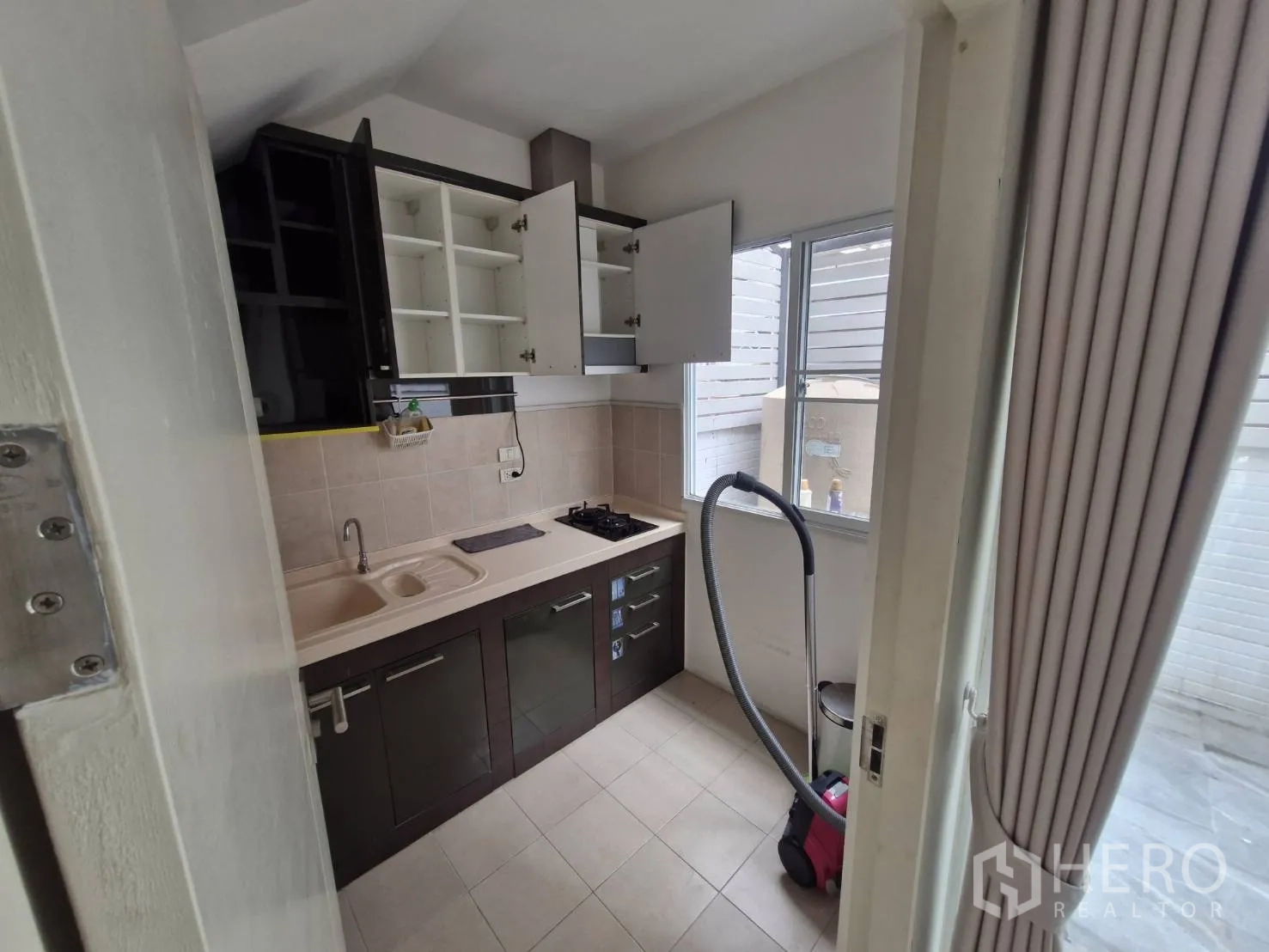 Townhouse for sale in Rat Burana, Bangkok - Compact kitchen with upper cabinets, sink, and gas hob by the window.