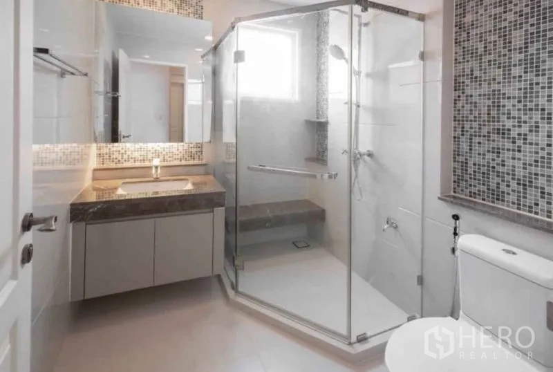 Detached House for rent or sale in Bang Phli, Samut Prakan - Modern bathroom with glass-enclosed shower, mosaic accent wall, vanity and toilet.