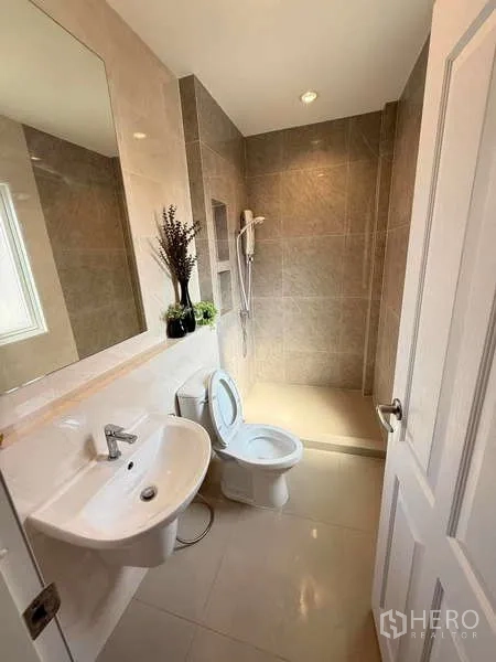 独立式住宅 出售在Bang Khen, Bangkok - 第二卫生间，宽大镜面、白色台盆、坐便器与步入式淋浴。