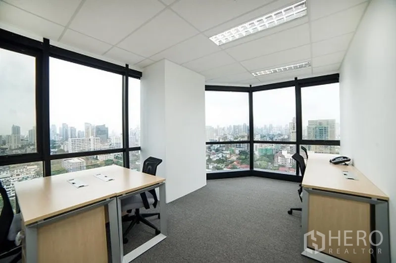 办公空间 出租在Khlong Toei, Bangkok - 转角办公室，环绕大窗与两张办公桌，俯瞰曼谷天际线。