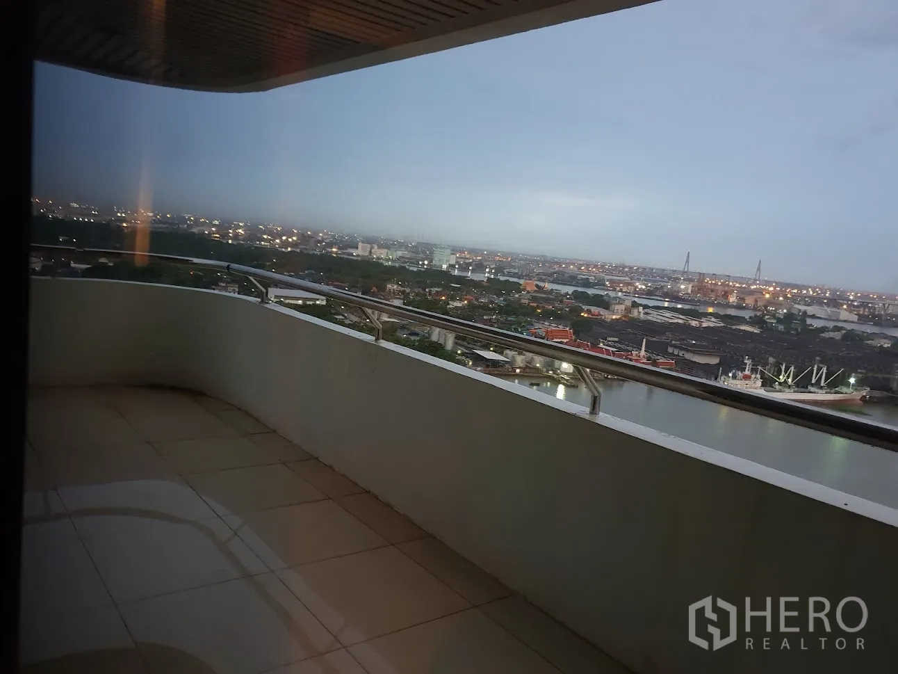 Condominium for rent in Yan Nawa, Bangkok - Curved balcony with stainless railing overlooking the river, city skyline and a bridge.
