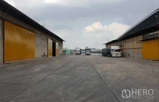 Warehouse for rent in Phra Pradaeng, Samut Prakan - Spacious concrete yard between warehouses providing wide truck access and loading space.