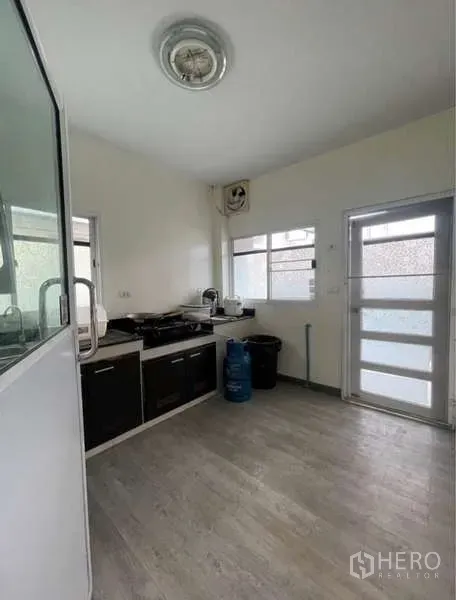 Detached House for rent in Bang Phli, Samut Prakan - Bright kitchen with built-in cabinets, gas hob, two windows and a side door.