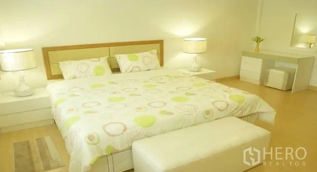 อพาร์ทเมนท์ ให้เช่าในKhlong Toei, Bangkok - ห้องนอนใหญ่เตียงคิงไซส์ โคมไฟหัวเตียง พื้นไม้โทนอ่อน และโต๊ะเครื่องแป้ง