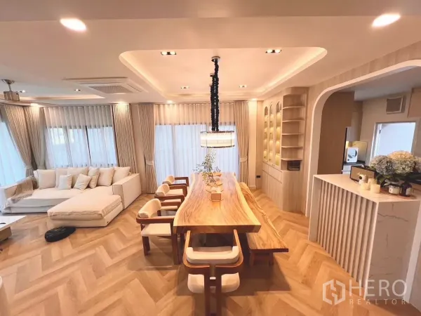 Detached House for rent in Bang Phli, Samut Prakan - Large dining table and lounge with full-height curtains, built-in shelves and soft lighting.