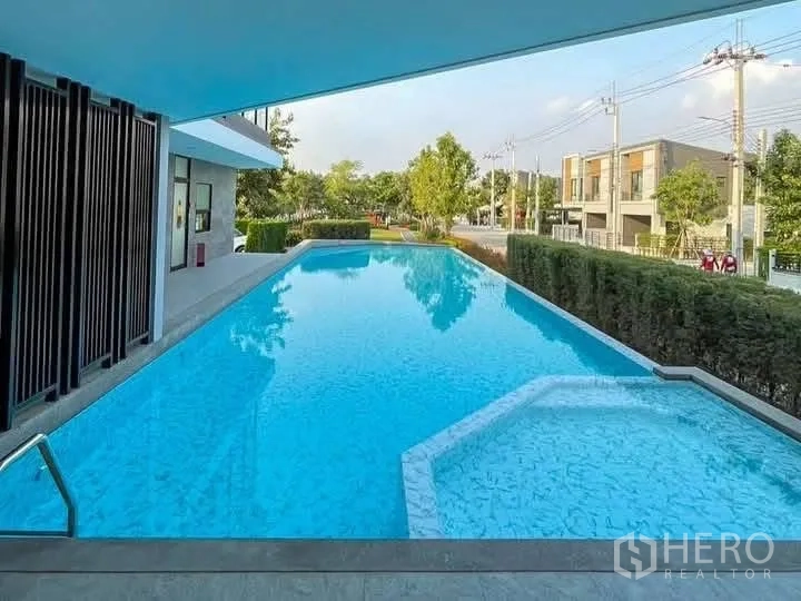 Townhouse for rent in Bang Phli, Samut Prakan - Outdoor swimming pool beside the clubhouse with views of the street and greenery.