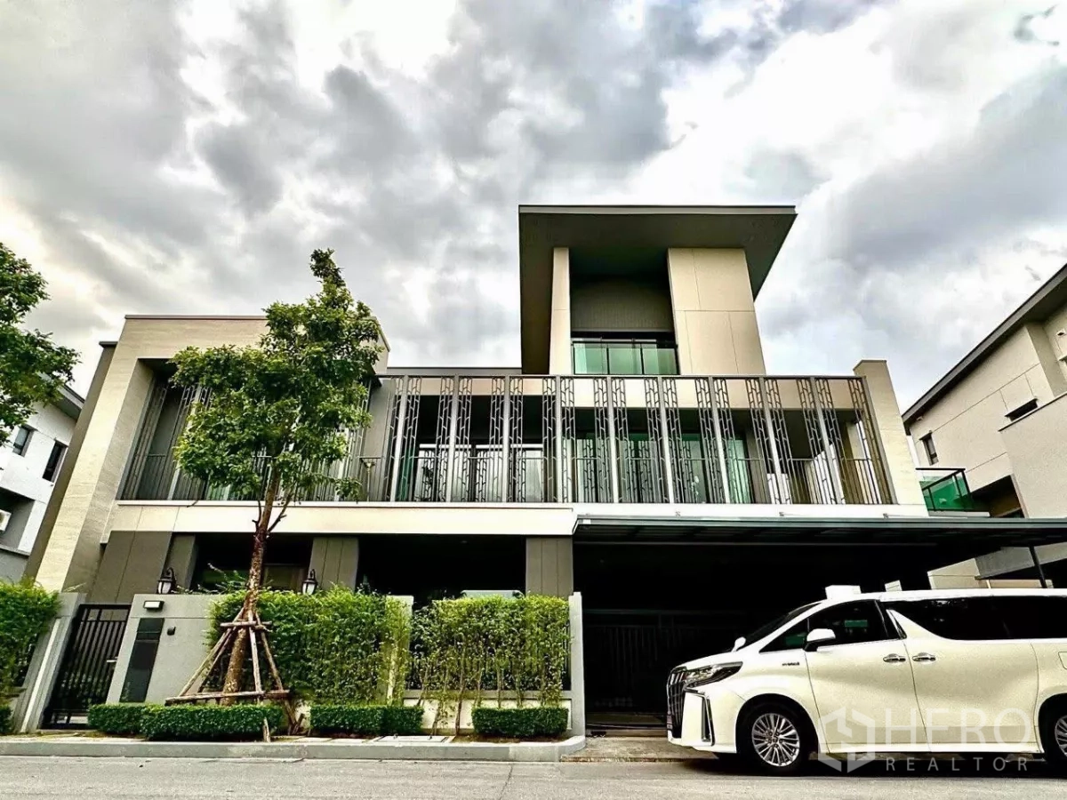 Detached House for sale in Saphan Sung, Bangkok - Modern detached house facade with tall metal screens, gated entry and carport with a white MPV at the front.