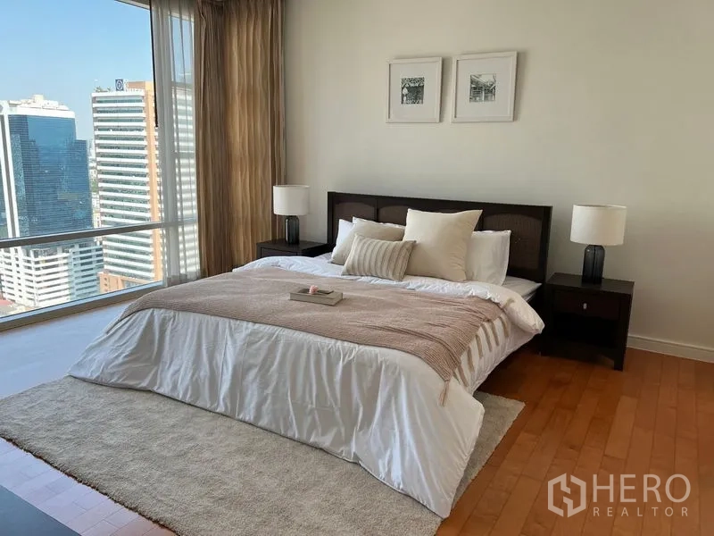 Condominium for rent in Watthana, Bangkok - Primary bedroom with king bed, wood flooring and full-height windows showcasing skyline views.